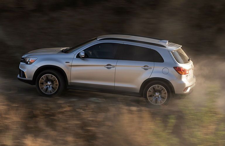 Profile view of silver 2019 Outlander Sport driving up hill