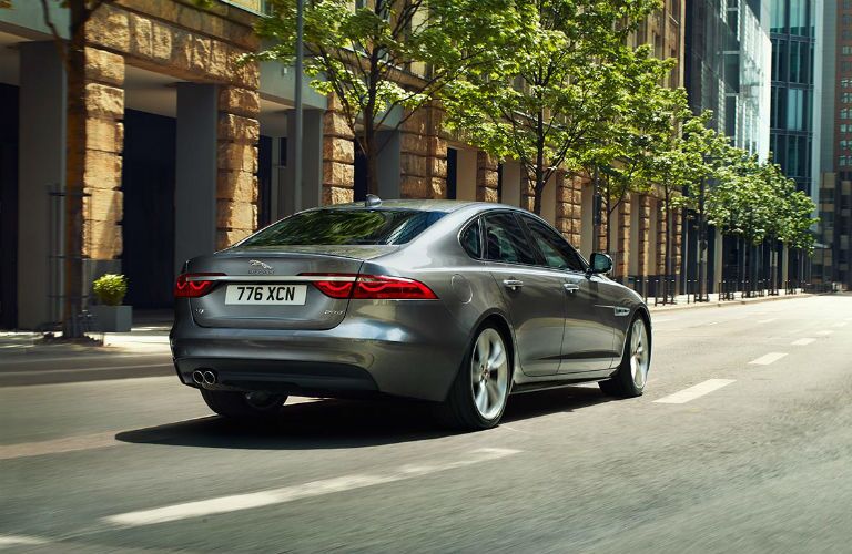 Rear view of 2018 Jaguar XF driving on tree-lined city street
