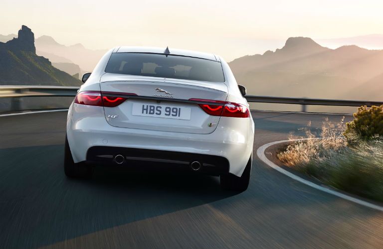 Jaguar XF driving on winding road with mountains in background