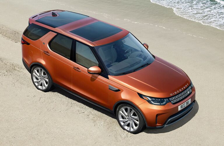 top-down view of orange Land Rover Discovery parked on beach