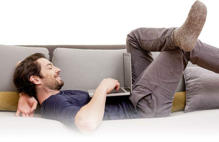 Male Shopper Shopping From Comfort of Home on Couch