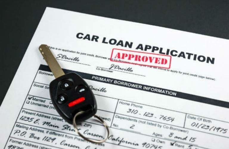 Set of keys and car loan papers with approved stamped on it