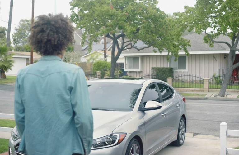 man looking at car in his driveway