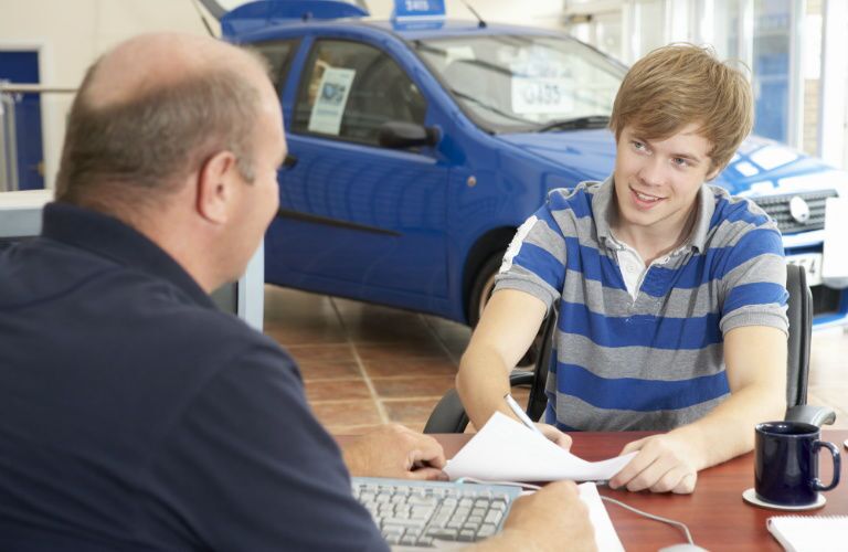 Young man signing papers for a used car loan
