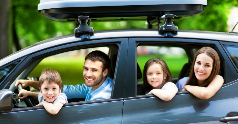 family of four looking out vehicle windows before leaving on a trip