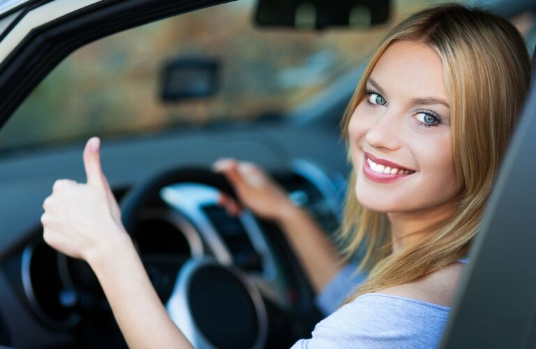 woman giving thumbs up from inside car