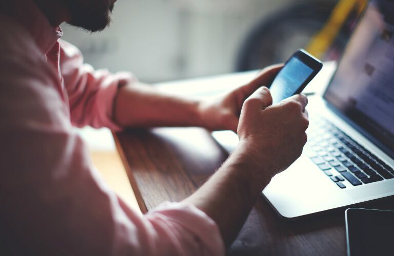 closeup of man looking at phone and computer