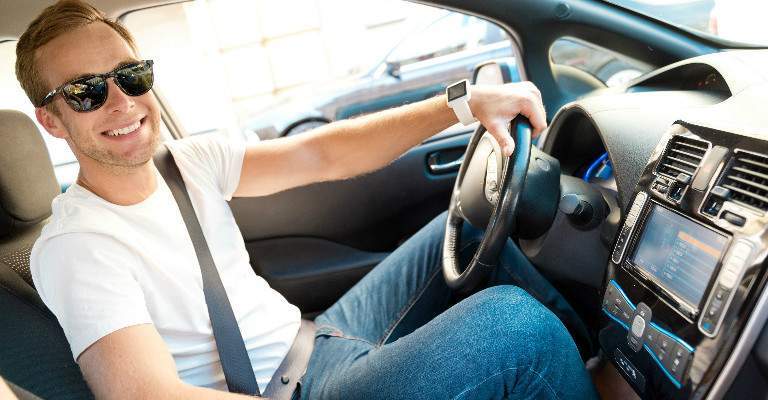 man wearing sunglasses while driving car and looking at camera