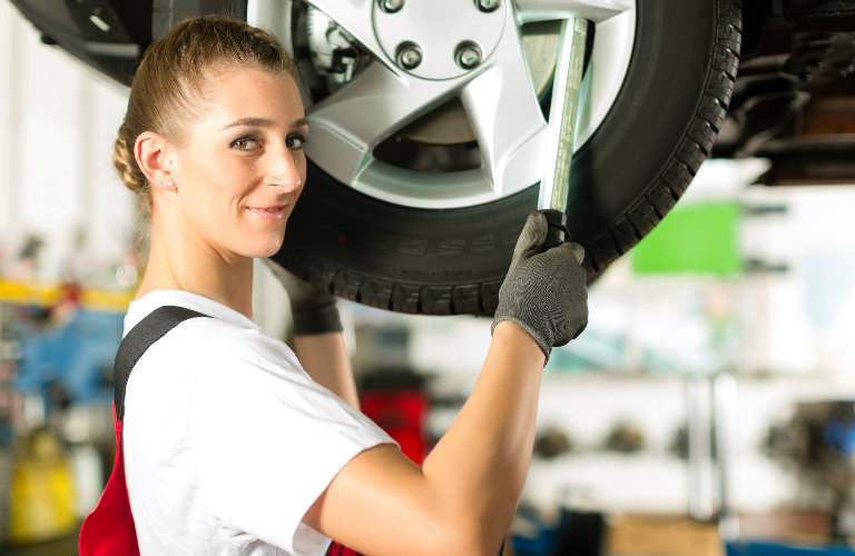 mechanic checking a tire and looking at camera