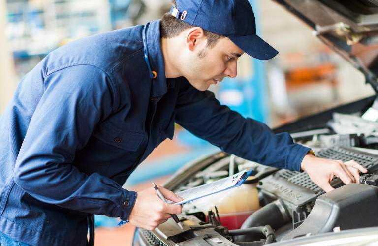 mechanic working under hood of car