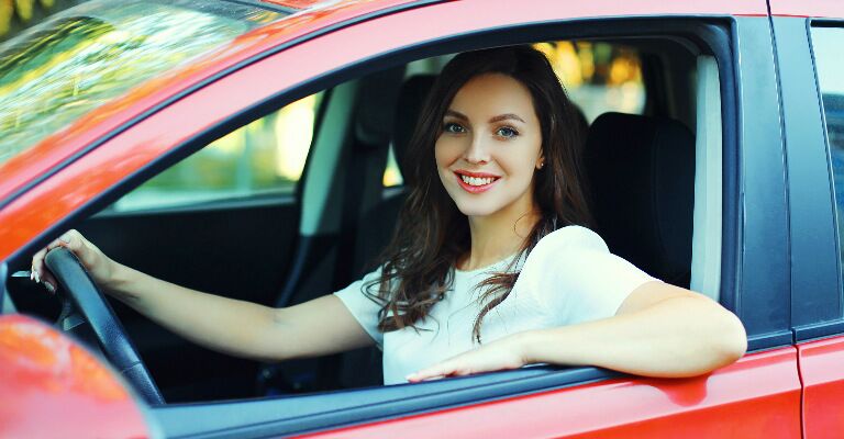 woman in red car smiling at camera