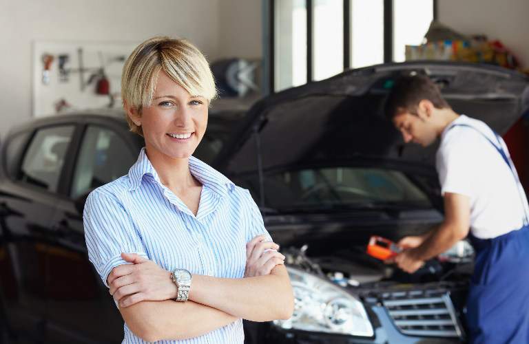 woman standing in front of mechanic working on her car