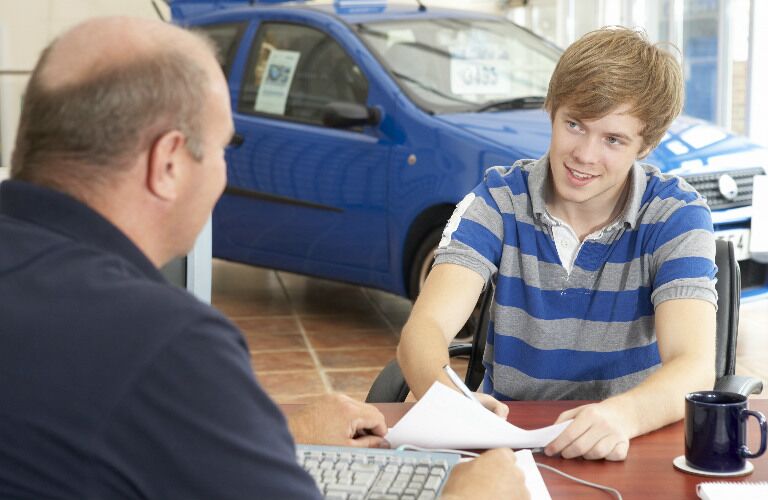 young man in auto dealership filling out paperwork