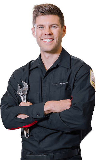 Smiling mechanic with arms crossed holds a wrench.