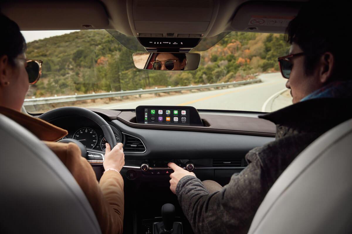 Two people sitting in a Mazda CX-30 driving down the highway near Edinburg, TX