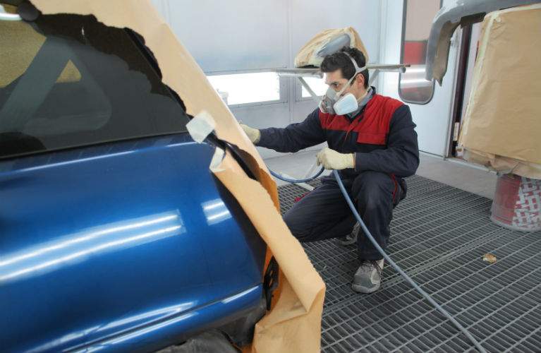 Young mechanic carefully fixing a paint job