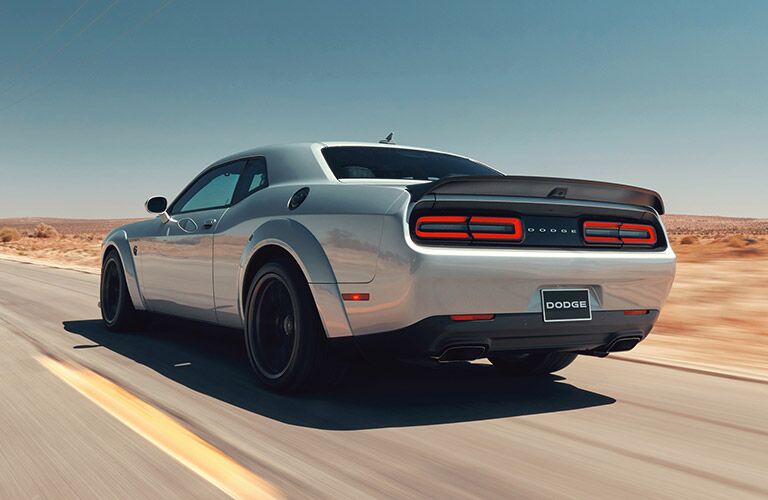 2019 Dodge Challenger driving on a desert highway seen from the rear driver side