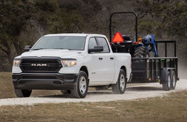 2019 Ram 1500 towing a tractor on a trailer