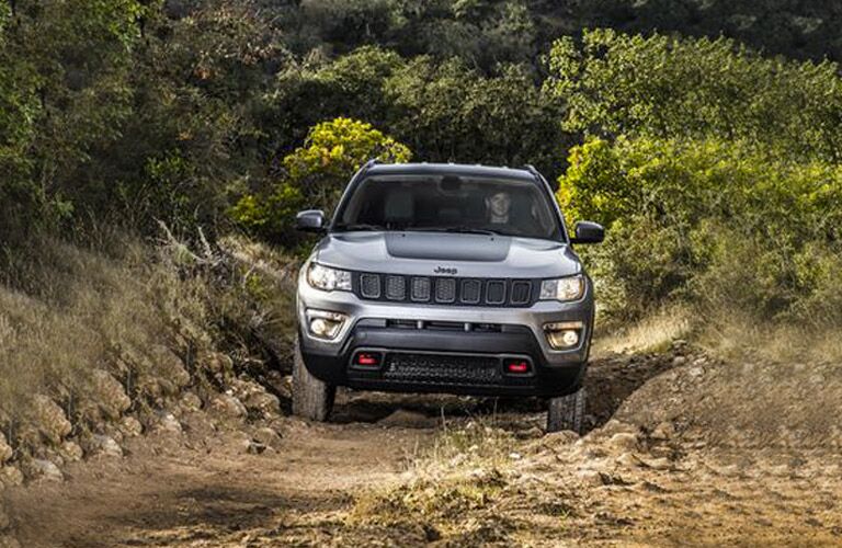 front view of silver 2018 jeep compass driving on dirt trail