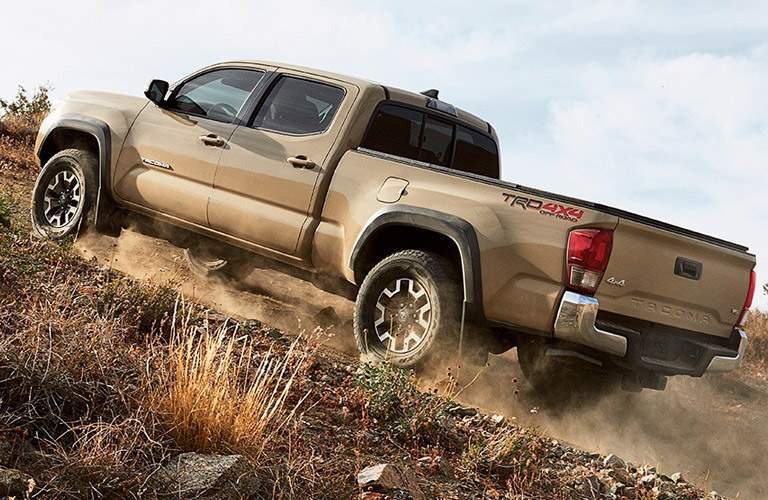 Tan Toyota Tacoma scaling up hill