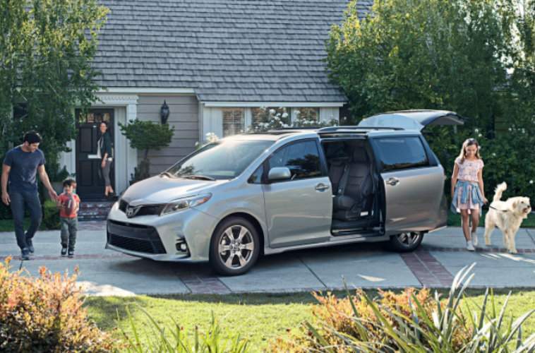 Family and dog walking around silver Toyota Sienna