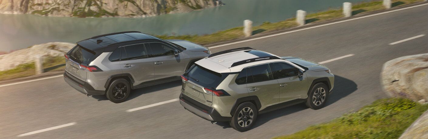 Two 2019 Toyota RAV4 models driving on waterfront road