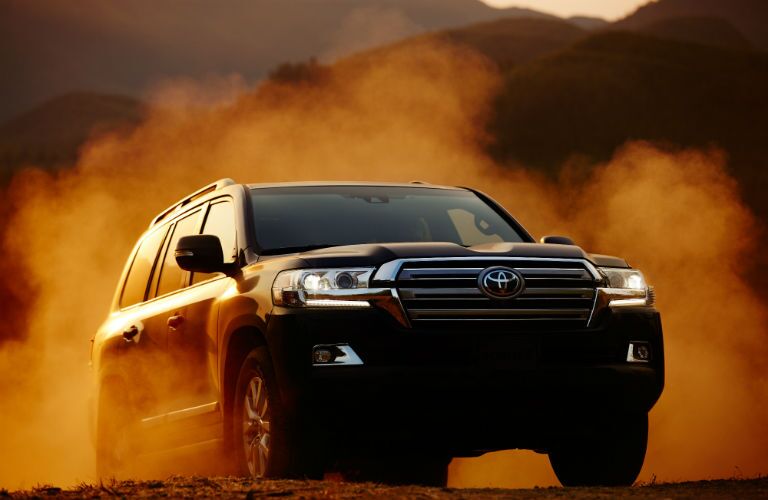 A head-on photo of the 2018 Toyota Land Cruiser crossing a dusty trail.