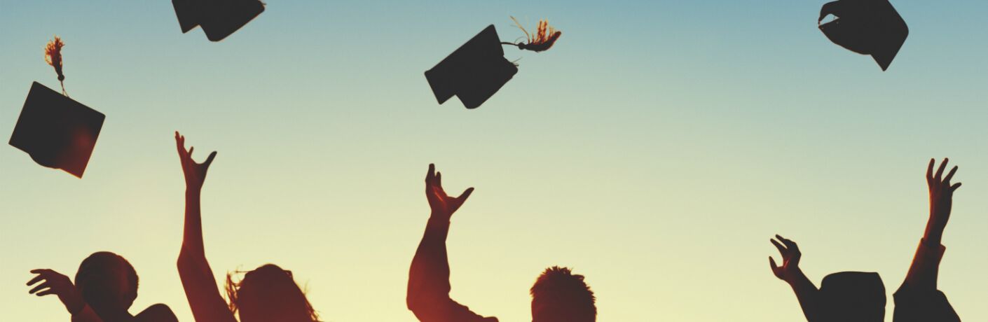 silhouette of graduates throwing caps in the air