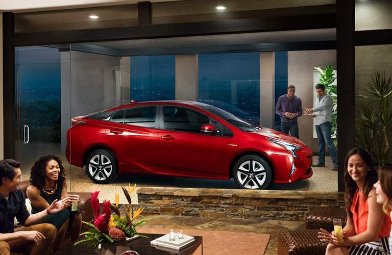 People in a building with the 2018 Toyota Prius outside