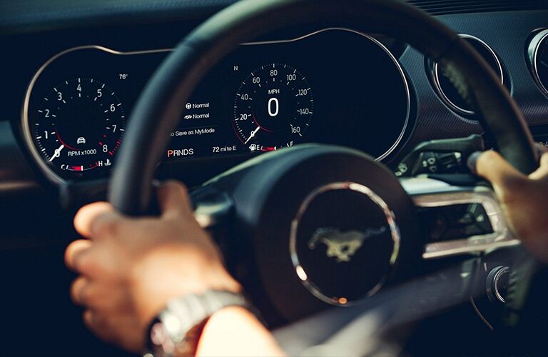 A man holding the steering wheel of the 2019 Ford Mustang