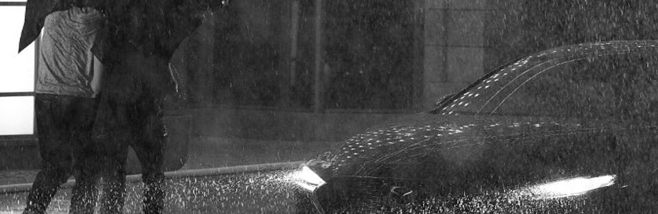 Two people running through heavy rain to running 2019 Mazda3