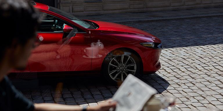 2019 Mazda3 driving in front of a building on a city street