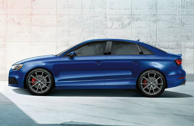 side profile of blue Audi S3 in front of concrete wall