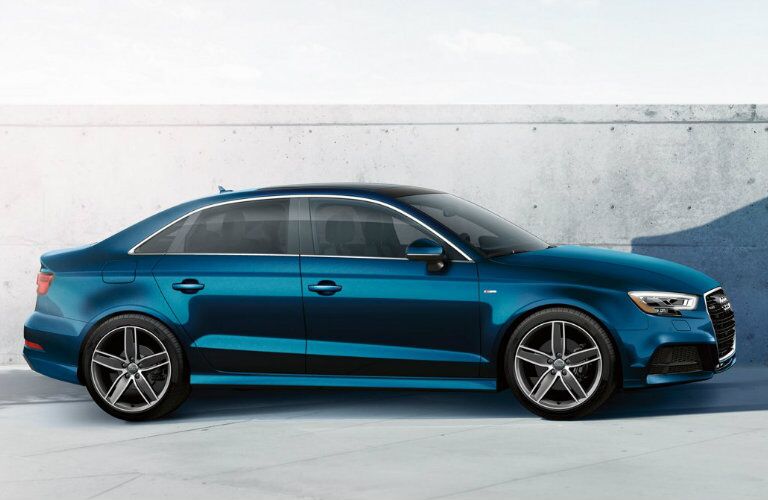 side profile of blue Audi A3 parked by concrete wall
