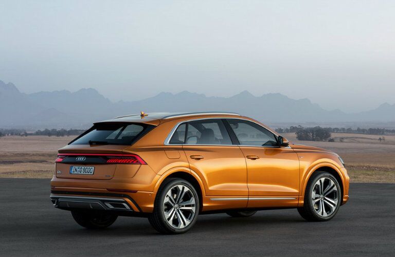 side profile of orange Audi Q8 parked in front of hazy mountain