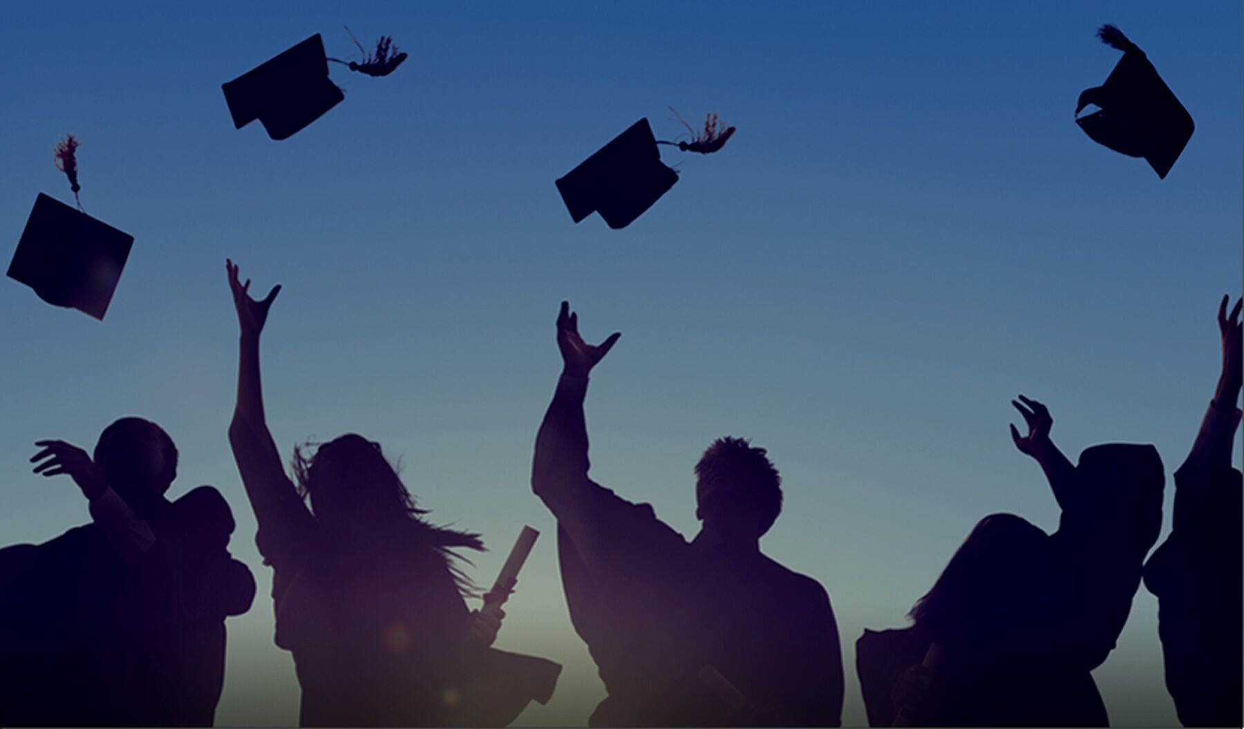 People throwing graduation caps into the air