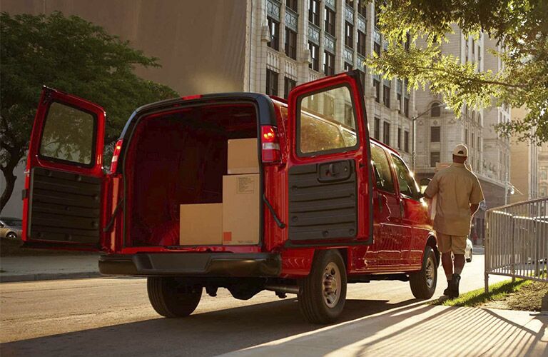 2017 Chevy Express cargo van parked on the side of the road with the rear doors open_o