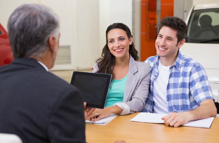 couple talking to a car dealership representative