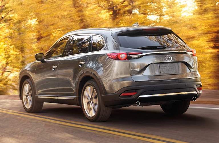 Gray 2018 Mazda CX-9 Rear Exterior Driving on Highway with Fall Foliage in Background