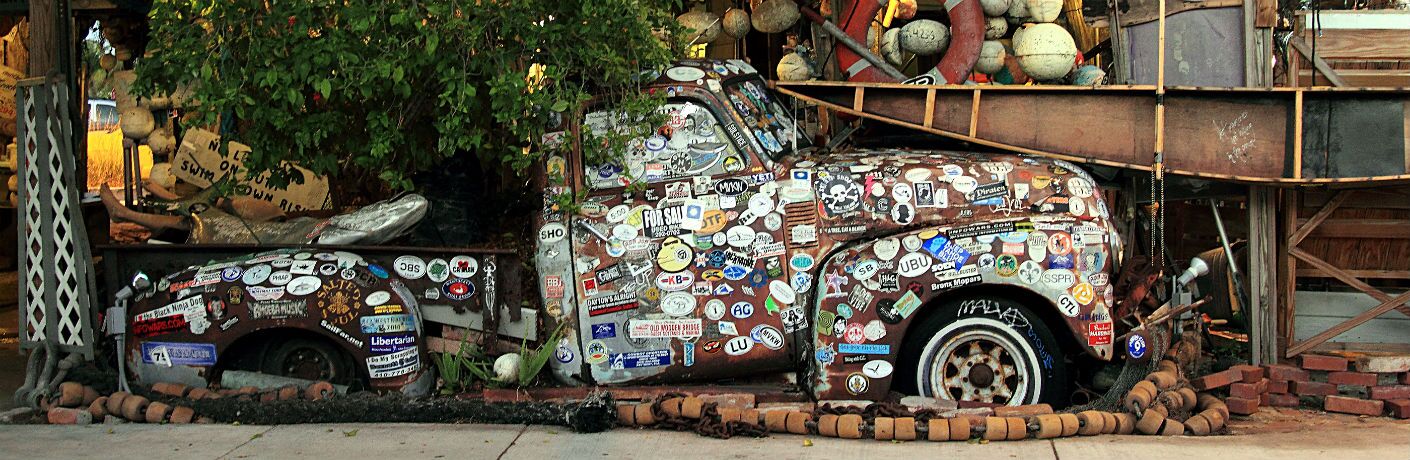 Image of an old truck sitting in the front yard covered in bumper stickers