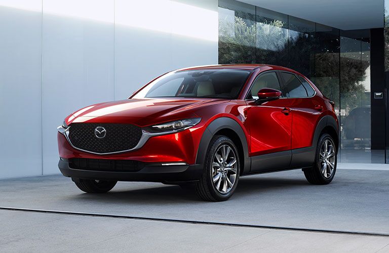 A front and side view of a red 2020 Mazda CX-30 parked near a concrete building.