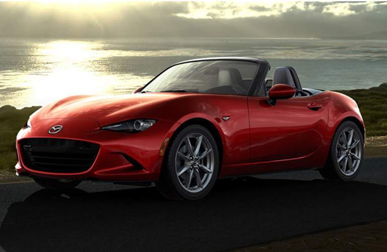 red mazda miata on road near water