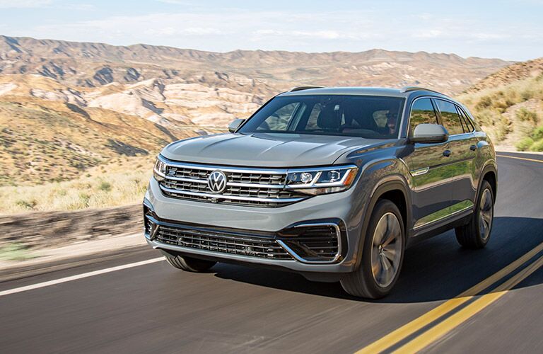 2020 Volkswagen Atlas Cross Sport exterior shot with light gray stone paint color driving on a country highway in a desert land
