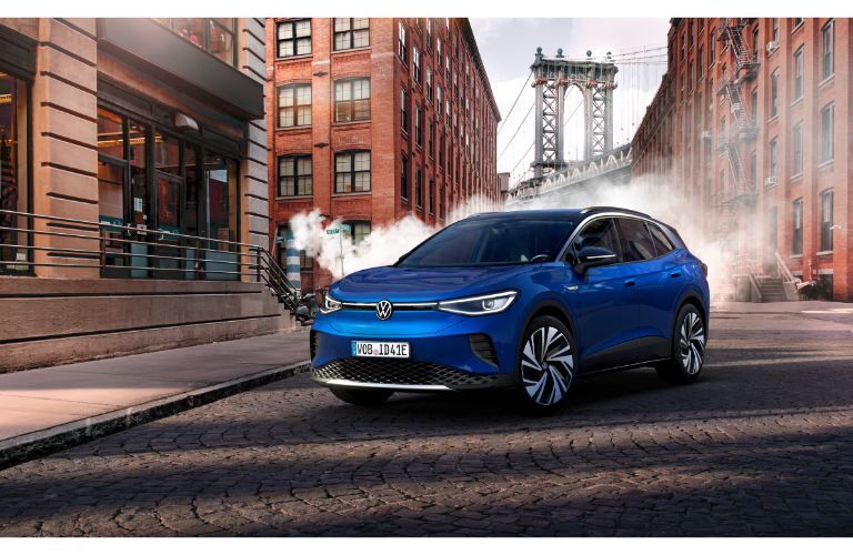 2021 Volkswagen ID.4 exterior shot with blue paint color parked on a cobblestone road with fog and brick buildings in the background