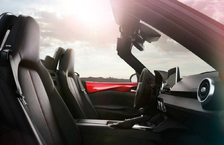 2018 Mazda MX-5 Miata interior front seating upholstery and dashboard features with sun glare in the clouds above