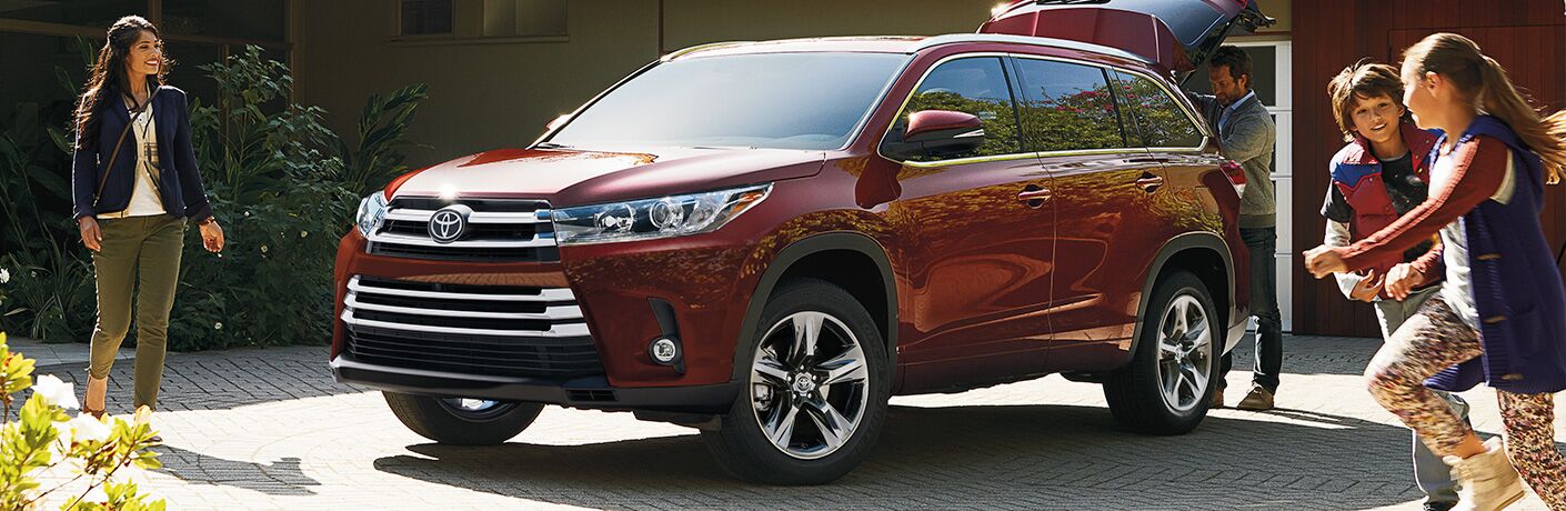 2019 Toyota Highlander parked in a driveway with a family