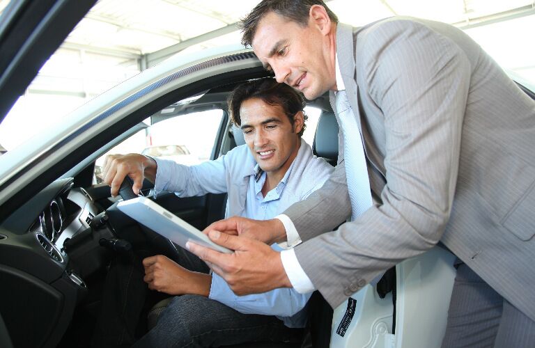 Car shopper and car dealer looking at a tablet
