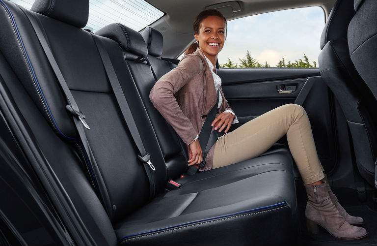 young woman buckling in back seat of 2018 Toyota Corolla