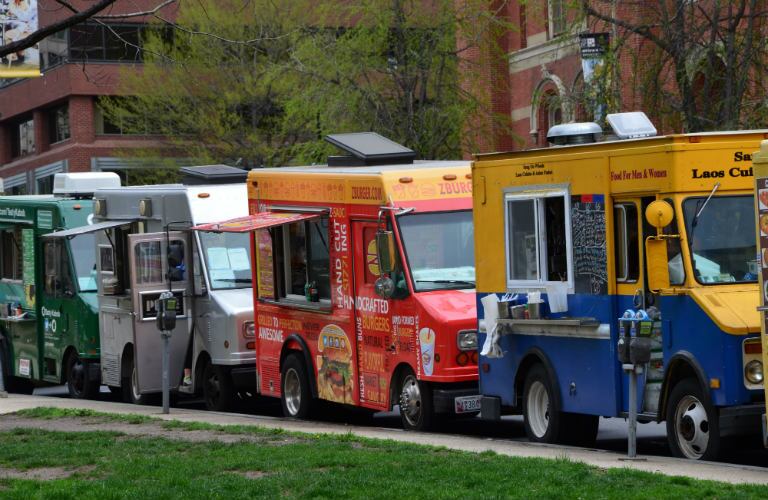 food trucks lined up on a street ready to feed eager crowds