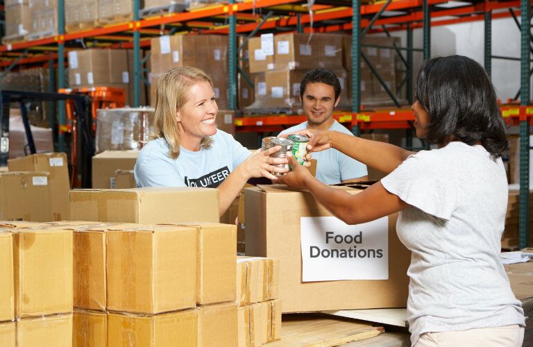 people collecting food donations in paper boxes